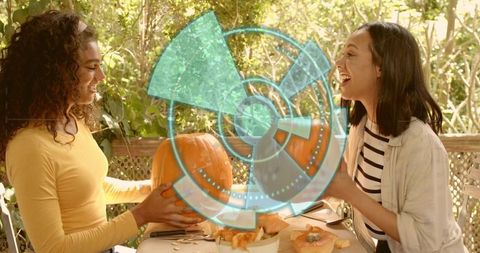 Friends carving pumpkins on sunlit porch with augmented reality hologram overlay