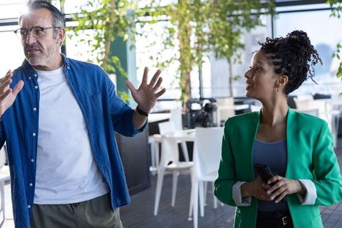 Multicultural colleagues collaborating in modern office lounge holding phone and glasses