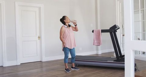 Senior woman prepares for workout on treadmill at home