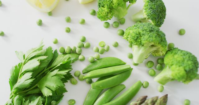 This bright and vibrant assortment of fresh green vegetables, including broccoli, peas, snap peas, and celery on a white background, captures a clean and healthy aesthetic. Ideal for use in health and wellness websites, vegan lifestyle blogs, cooking tutorials, nutrition articles, and marketing for organic produce.