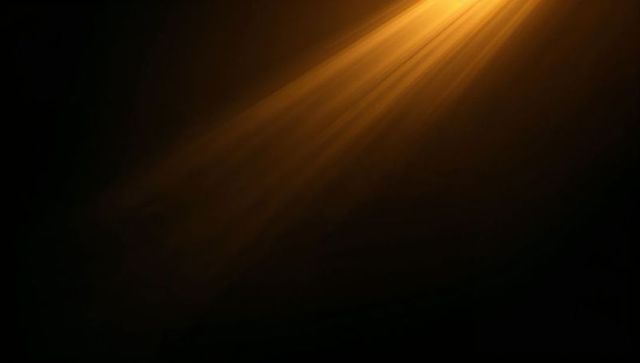 Golden light beam angling across dark background with soft rays, dust and copy space