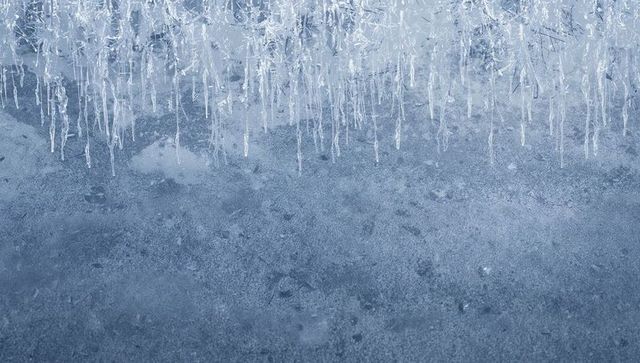 Hanging crystalline icicles on frosted overhang, blue-gray ice texture and frost crystals