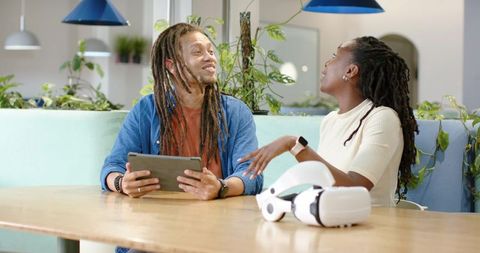African American coworkers collaborating with tablet and VR headset in coworking lounge