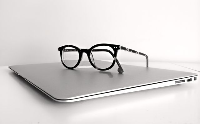Eyeglasses resting on sleek closed laptop on white surface - Download Free Stock Photos Pikwizard.com