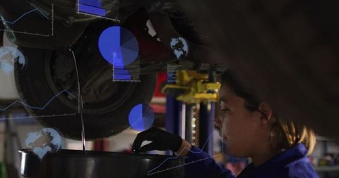 Female mechanic draining engine oil under vehicle wearing gloves in auto repair workshop