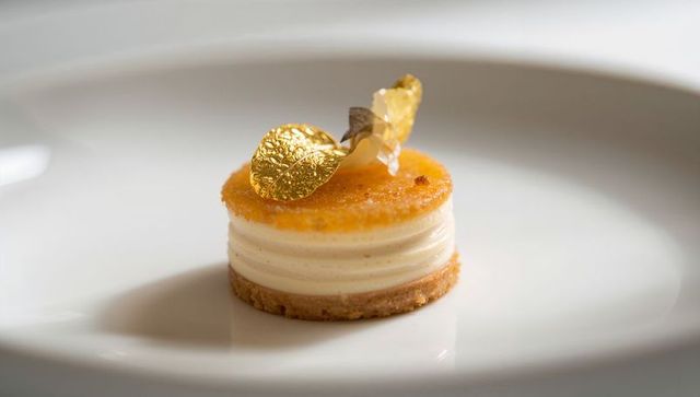 Serving miniature layered mousse entremet topped with gold leaf on white plate