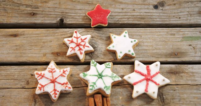 Star-shaped cookies with festive icing designs are displayed on a rustic wooden surface, symbolizing holiday treats and homemade baking traditions. Their colorful patterns add a cheerful touch to seasonal celebrations.