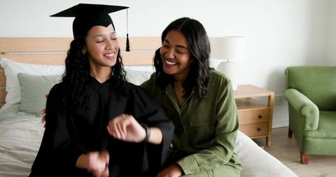 Graduate Daughter Showing Smartwatch to Mother in Joyful Moment