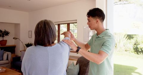 Young physiotherapist assisting senior with shoulder exercise
