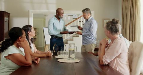 Senior Man Receiving Award Surrounded by Grateful Friends
