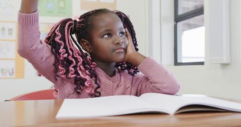 Curious Girl in Classroom Raising Hand by Open Book