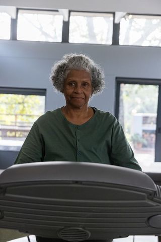 Senior woman exercising on treadmill in bright gym