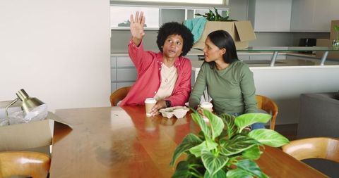 Couple Drinking Takeaway Coffee Discuss Moving Plans at Kitchen Table
