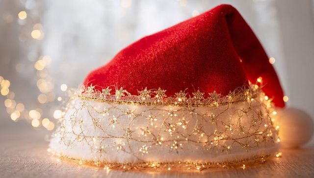 Resting red velvet santa hat wrapped in gold lace and warm fairy lights