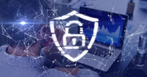 Mature man monitoring cybersecurity analytics on laptop with shield padlock hologram UI