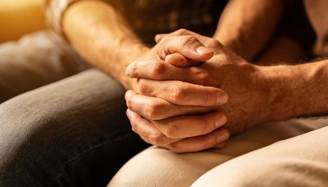 Clasping hands resting on lap during golden hour closeup comfort and intimacy