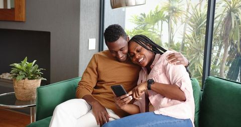 African american couple bonding with smartphone in living room