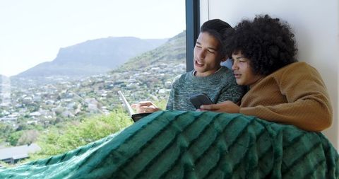 Diverse Friends Relaxing by Window with Scenic Cityscape
