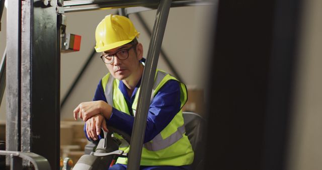 Warehouse worker in safety attire driving a forklift. Perfect for illustrating topics on occupational safety, warehouse operations, industrial work environments, and logistics. Useful for training materials, safety manuals, and articles on workplace safety.