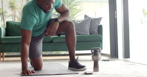 Man Kneeling on Yoga Mat Checking Smartwatch for Workout
