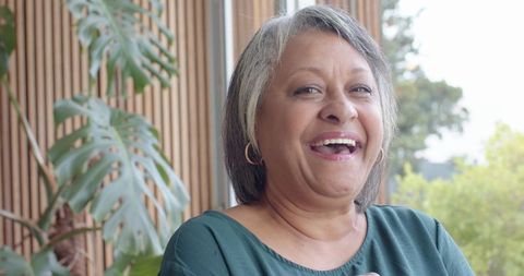 Joyful Senior Woman Relaxing by Window with Indoor Plants