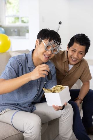 Asian father and son celebrating birthday at home with gift unboxing and car key surprise