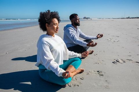 Diverse friends practicing beach meditation for serenity and relaxation