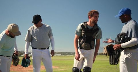 Diverse baseball players preparing for practice on sunny grass field