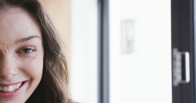 Woman with a smile, showing scars on face, standing near window. Natural light enhances her features, adding warmth and authenticity. Perfect for campaigns focusing on self-acceptance, confidence, inner beauty, medical awareness, and positive mental health.