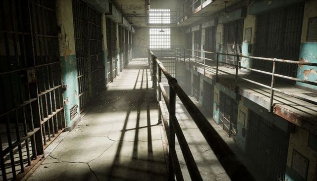 Sunlit abandoned prison cellblock with rusted railings, cracked concrete and dusty bars