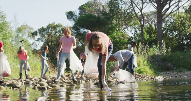 Group of volunteers cleaning a riverbank by picking up litter and plastic waste bags. Involves teamwork and environmental conservation efforts. Suitable for illustrating community service, sustainability, and environmental stewardship. Ideal for articles or campaigns promoting eco-friendliness, teamwork, and public awareness.