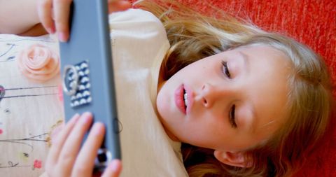 Girl Focused on Smartphone Lying on Red Couch - Download Free Stock Images Pikwizard.com