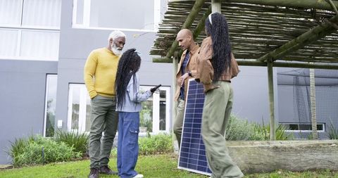Diverse Family Installing Solar Panel and Teaching Child About Clean Energy