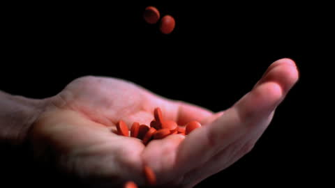 Red Pills Dropping Into Hand Captured in Slow Motion