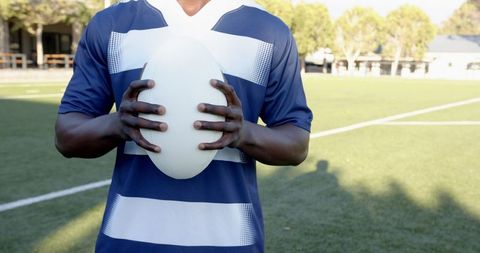 Rugby player holding ball on field in daylight