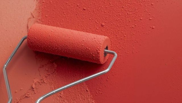 Red Paint Roller Creating Textured Finish on Interior Wall