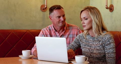 Middle-aged Couple Collaborating on Laptop in Cozy Cafe