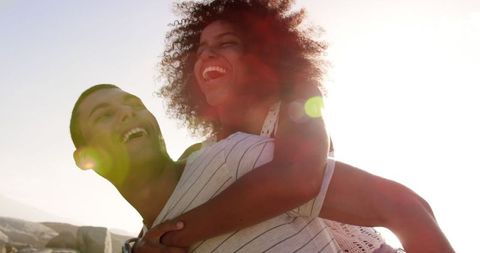 Joyful Beach Piggyback Ride with Interracial Couple