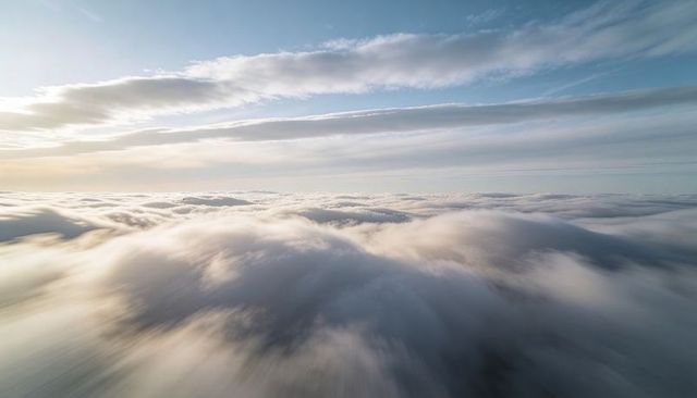 Sunlit stratocumulus sea drifting toward horizon over vast layered cloudscape calm panorama