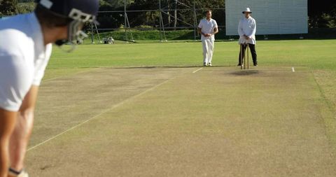 Batsman Facing Bowler with Umpire on Cricket Pitch Outdoors