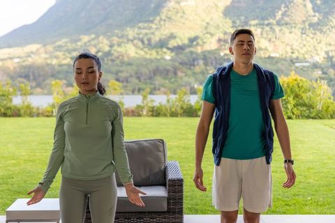 Diverse couple practicing breathwork and mindfulness on lakeside patio