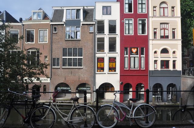 Lively street scene showcasing a row of parked bicycles in front of colorful traditional Dutch houses along a canal in Utrecht, Netherlands. Ideal for materials on European travel, urban exploration, architecture, cultural experiences, and city life.
