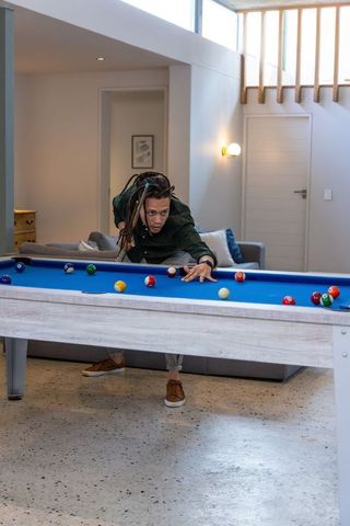Focused african american man aiming shot on blue felt pool table in modern loft