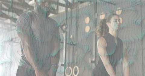 Two trainers flexing with wooden rings in gym showing strength and partnership