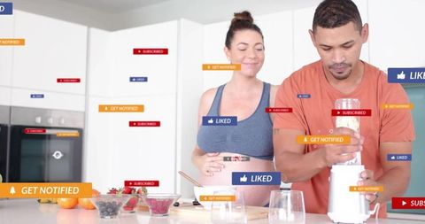 Expecting couple blending smoothies in minimalist kitchen with social media alerts
