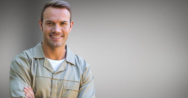 Portrait of smiling serviceman standing against grey background