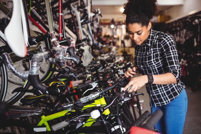 Female mechanic examining and maintaining bicycles in a workshop, suitable for themes related to bike repair services, professional mechanics, and transportation maintenance. Ideal for illustrating bicycle maintenance businesses or showcasing professional repair services.