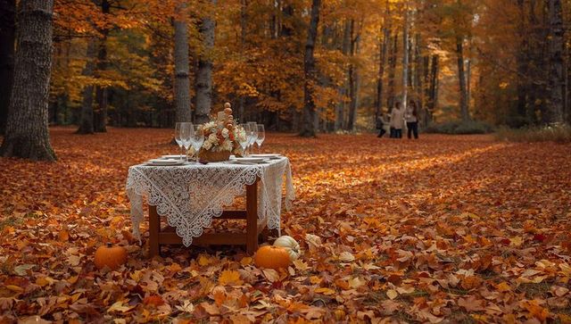 Lace table setting in autumn forest with pumpkins, wine glasses and floral centerpiece