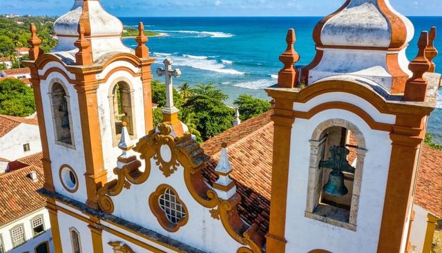 Baroque church bell towers overlooking azure coast with ornate stucco and terracotta roofs