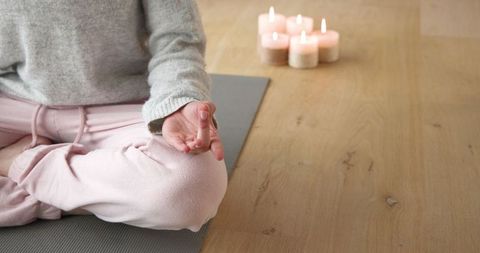 Young Woman Meditating with Candles in Relaxing Studio Atmosphere